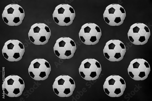 Three-dimensional pattern of balls.Black and white soccer balls flying in the air, isolated on a dark background. The concept of object levitation. Minimalistic concept of sports, three-dimensional im © Natalia