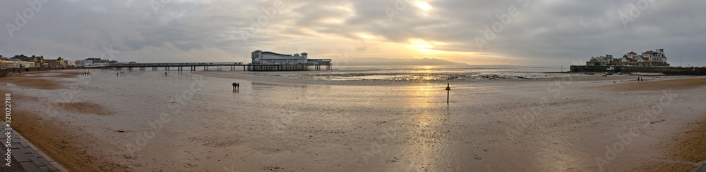 Weston-super-Mare, UK - December 26, 2019: The Grand Pier is a pleasure pier on the Bristol Channel approximately 18 miles southwest of Bristol. Winter view with low tide and cloudy weather