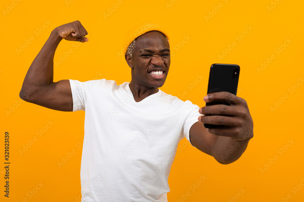 handsome strong black american man taking selfie on phone showing muscles on orange background handsome strong black american man taking selfie on phone showing muscles on orange background