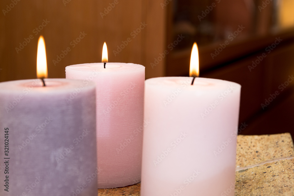 Group of three burning candles in the home. Candles of pink tones in a warm house Group of three burning candles in the home. Candles of pink tones in a warm house