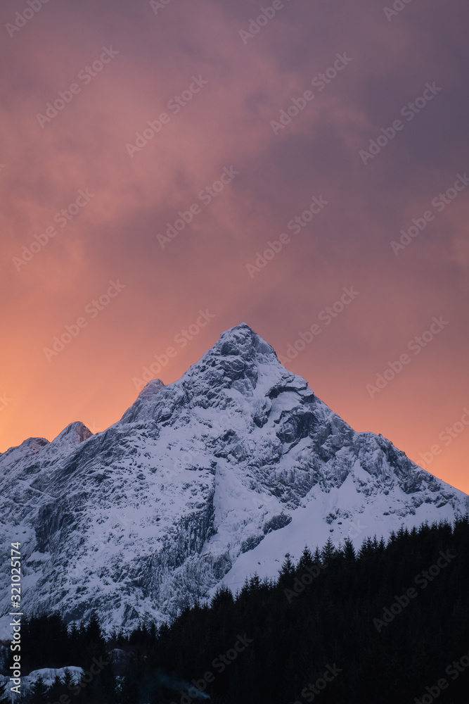 Skottinden mountain during winter and during amazing sunset with orange sky. The mountain in next to Ballstad town in Lofoten islands in North of Norway
