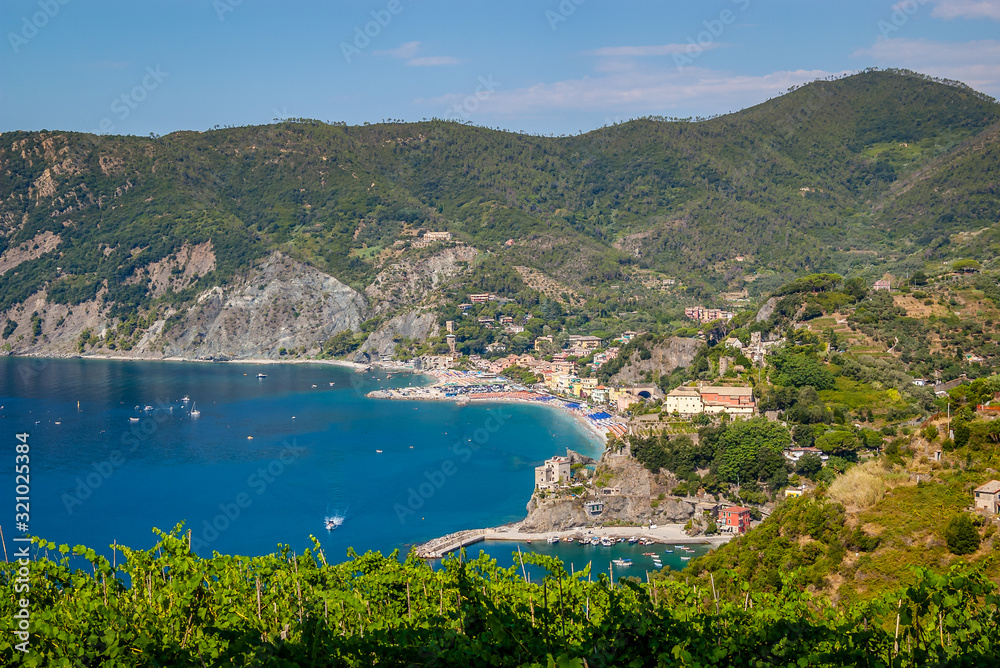 A beautiful view of the Cinque Terre trail to the village of Monterosso al Mare his beach with the blue sea and vineyards in the foreground. Photo taken August 2018,Liguria, La Spezia ,Italy.