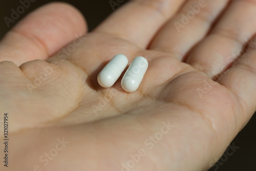 Two white medical capsules of medicine in the palm of hand. Medical background