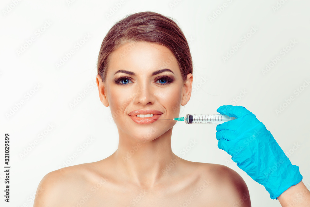 Woman smiling looking at you while hand in gloves with syringe of filler for lips about to fill the hyaluronic acid silicone isolated White background Woman smiling looking at you while hand in gloves with syringe of filler for lips about to fill the hyaluronic acid silicone isolated White background