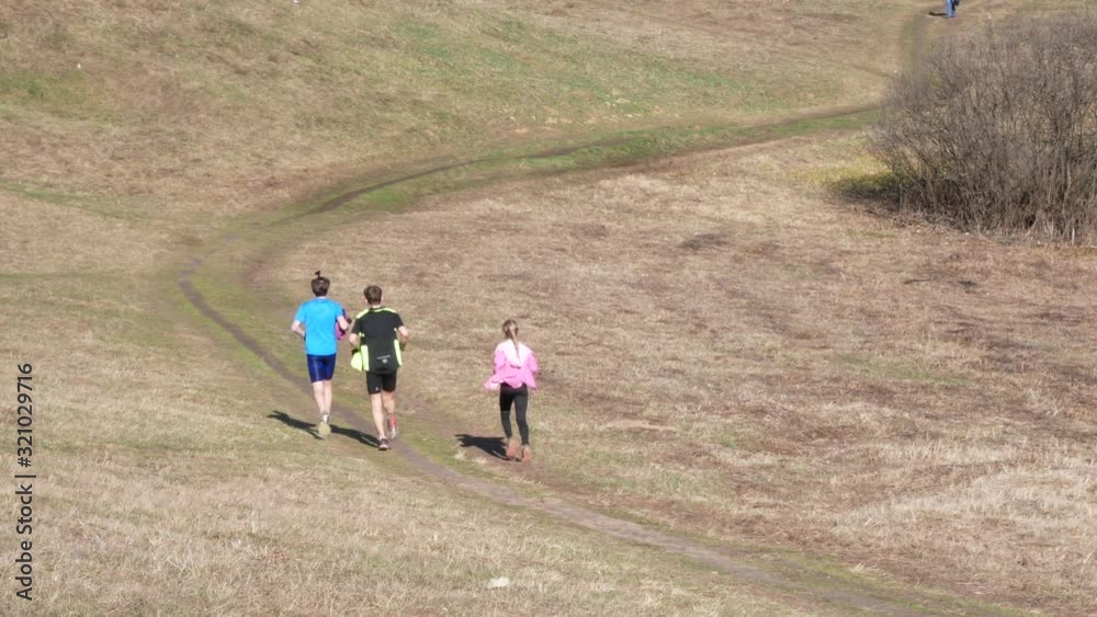 Teenagers running along a country road through a spring field Teenagers running along a country road through a spring field