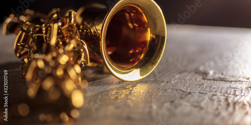 Golden colored saxophone. Close up of old retro things shooted with vintage style colors and toned. Flyer for your ad. Concept of retro style, history return, fashioned things, hobby, memories.