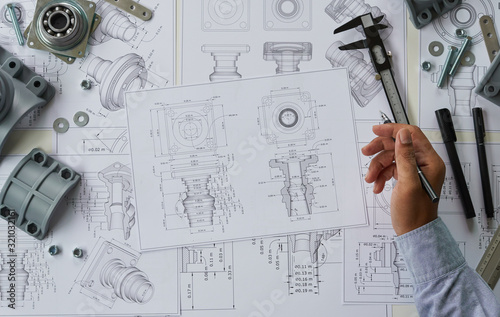Engineer technician designing drawings mechanical parts engineering Engine.manufacturing factory Industry Industrial work project blueprints measuring bearings caliper tools