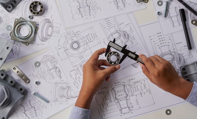 Engineer technician designing drawings mechanical parts engineering Engine.manufacturing factory Industry Industrial work project blueprints measuring bearings caliper tools