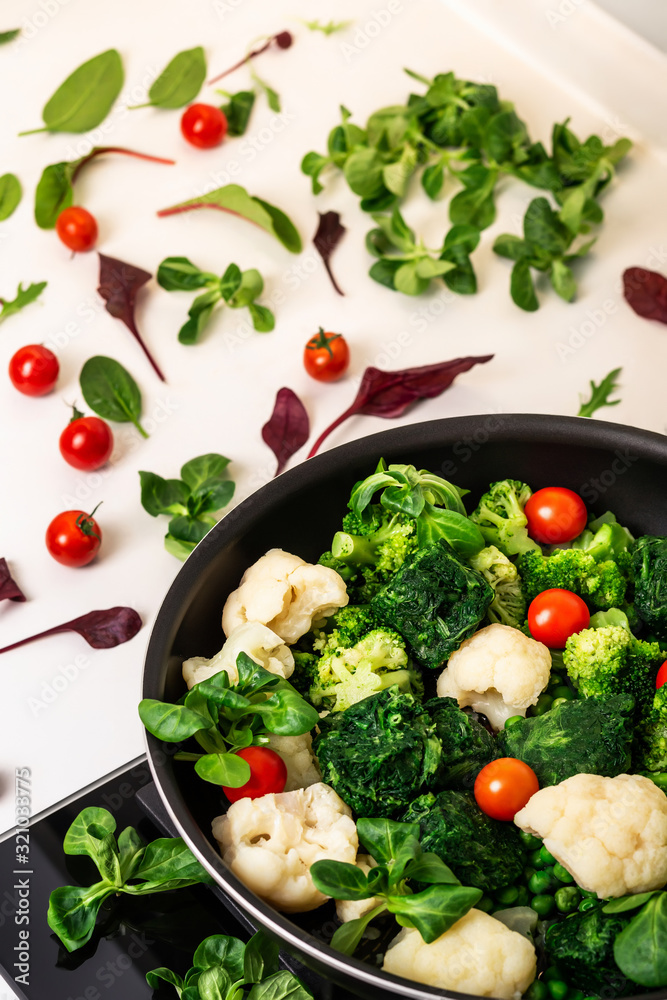 Cooking healthy organic food. Organic tomatoes, spinach, arugula, cauliflower and fresh green meat. Vegetarian food. Vegetables in a pan. Cooking healthy organic food. Organic tomatoes, spinach, arugula, cauliflower and fresh green meat. Vegetarian food. Vegetables in a pan.