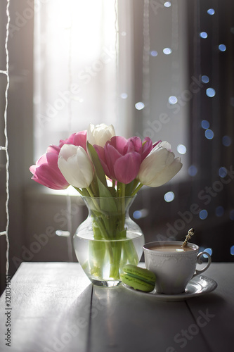 Pink and white tulips and a white Cup of coffee on a light table