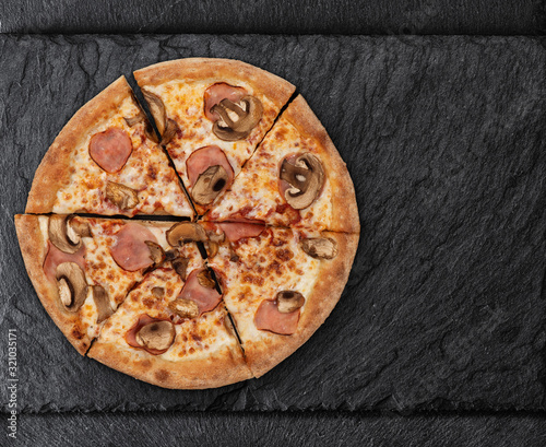 pizza with mushrooms and ham on a slate board