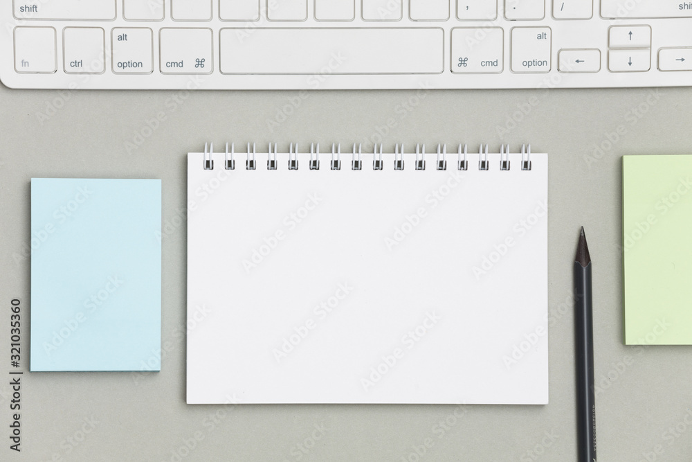 Blank notebook on grey background with keyboard, pencil and supplies. Blank notebook on grey background with keyboard, pencil and supplies.