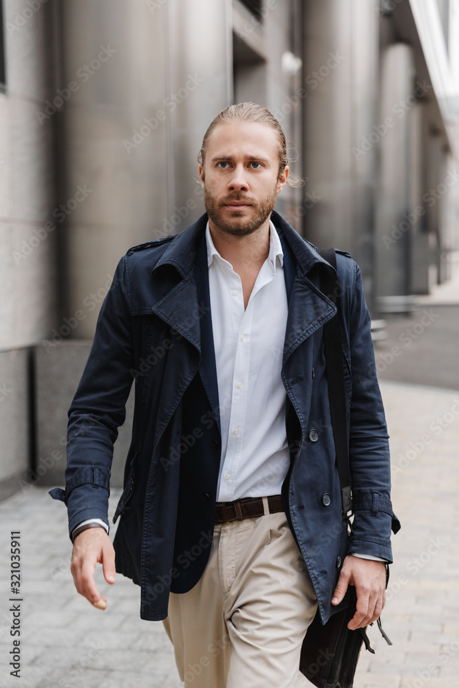 Attractive young bearded businessman walking outdoors Attractive young bearded businessman walking outdoors