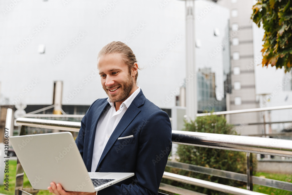 Handsome young bearded businessman standing outdoors Handsome young bearded businessman standing outdoors