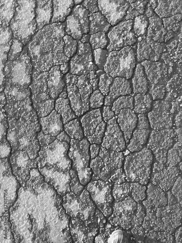 Cracks on the pavement as an abstract background. Black and white photo.
