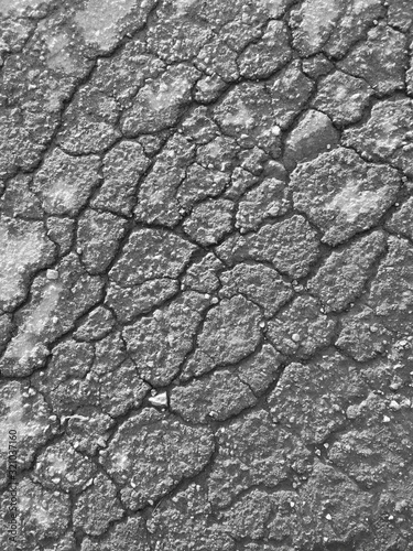 Cracks on the pavement as an abstract background. Black and white photo.