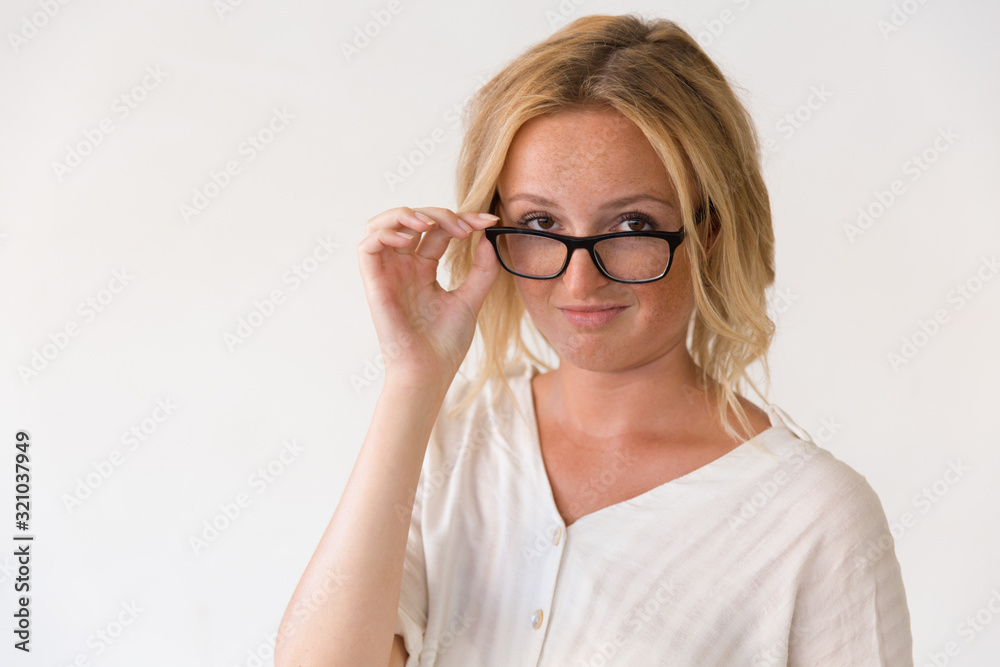 Attractive young woman adjusting eyeglasses. Portrait of confident young woman wearing spectacles and looking at camera isolated on white background. Business concept