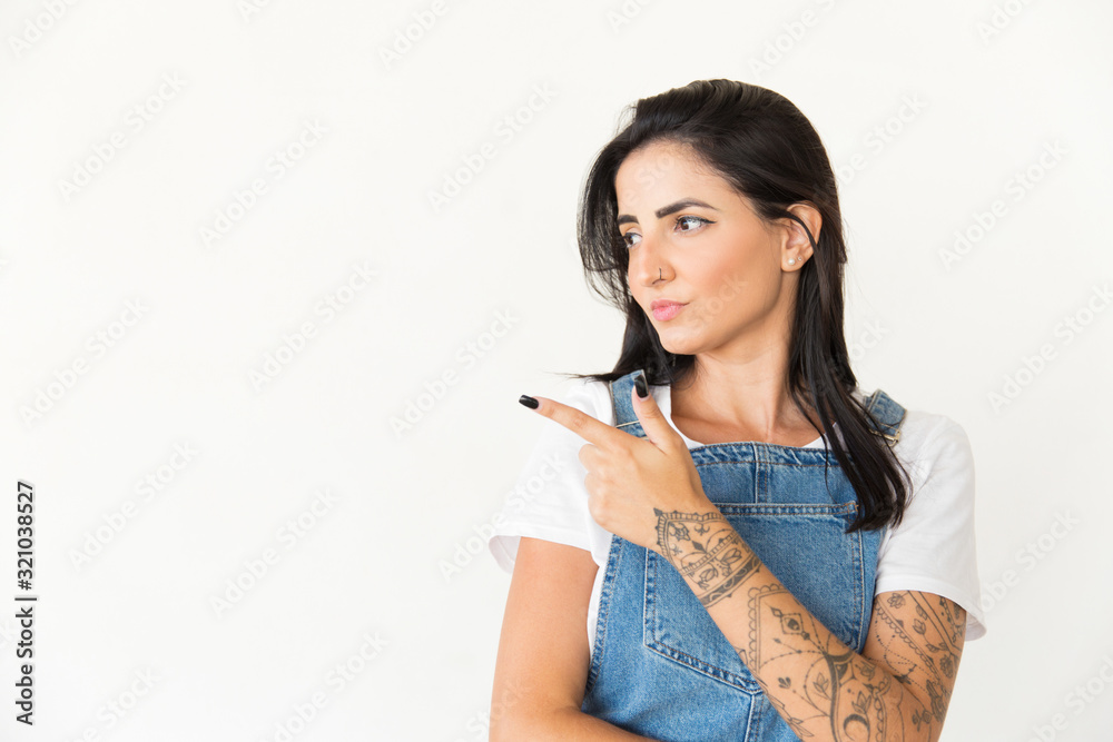 Attractive young woman pointing with finger. Beautiful young tattooed woman pointing away with finger isolated on white background. Promotion concept Attractive young woman pointing with finger. Beautiful young tattooed woman pointing away with finger isolated on white background. Promotion concept