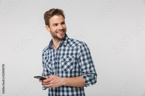 Portrait of happy young man smiling and using cellphone © Drobot Dean