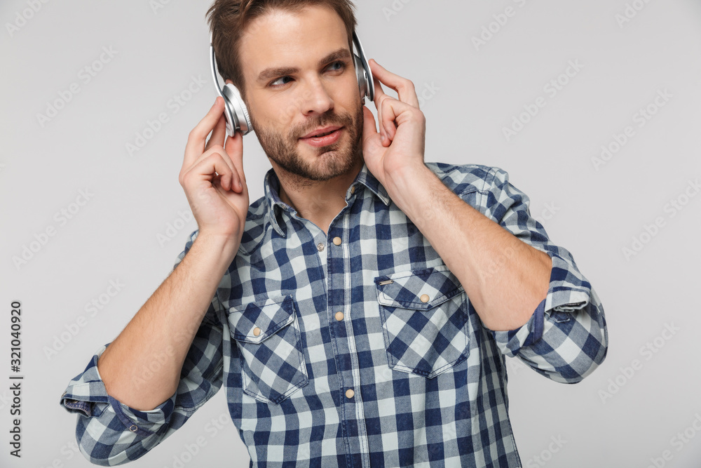 Portrait of caucasian young man wearing plaid shirt using headphones Portrait of caucasian young man wearing plaid shirt using headphones
