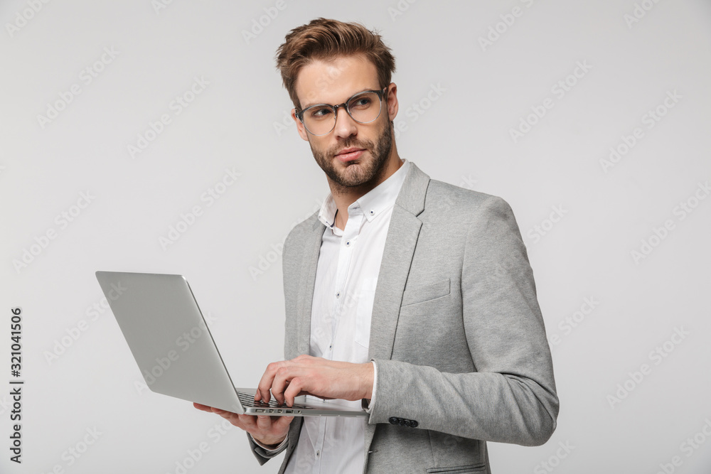Portrait of serious handsome man holding and using laptop