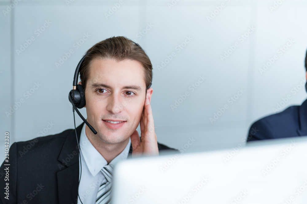 Smiling man working care customer service wearing headphone talking .with customer at call center office.Support Customer Team 24 hours Smiling man working care customer service wearing headphone talking .with customer at call center office.Support Customer Team 24 hours