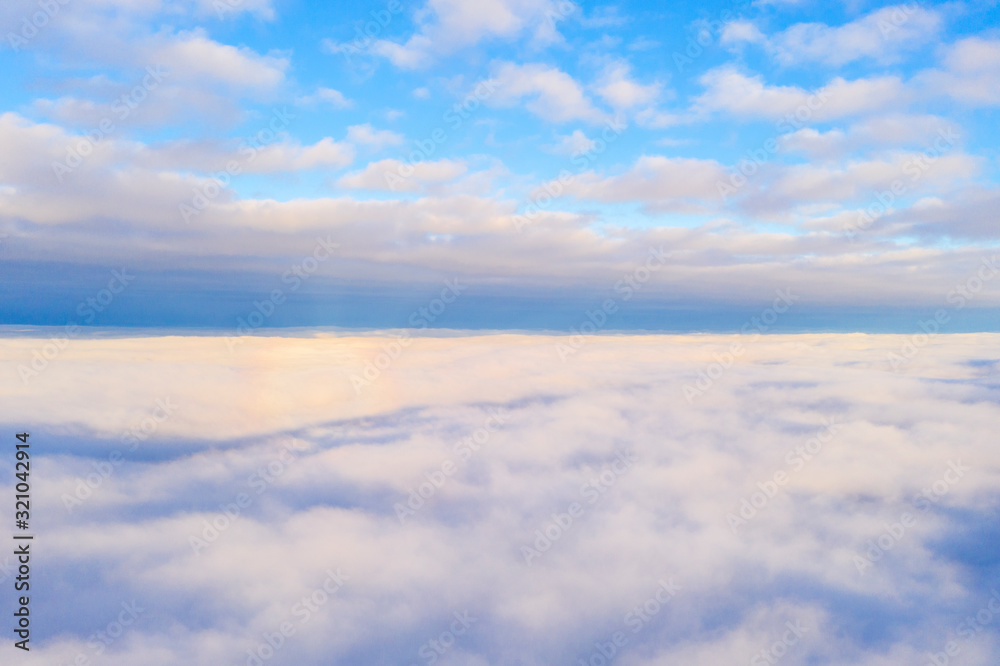 Aerial view White clouds in blue sky. Top view. View from drone. Aerial bird's eye view. Aerial top view cloudscape. Texture of clouds. View from above. Sunrise or sunset over clouds