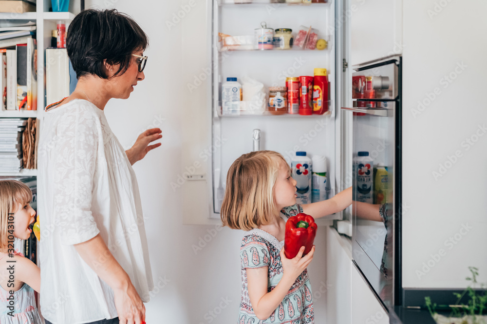 Beautiful female toddler helping her mother unpacking groceries Beautiful female toddler helping her mother unpacking groceries