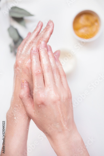 A young woman takes care of her hands with a scrub. Self care concept, hand care, body care