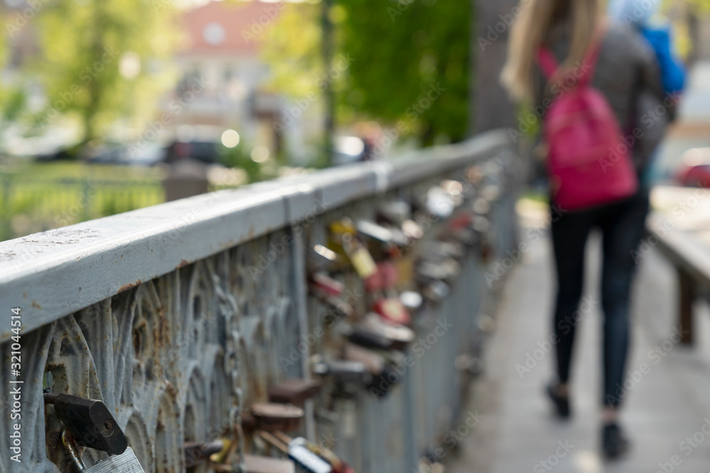 River bridge and locks. Various love stories in historical part of city. Blurry view of romantic place Uzupis. Vilnius downtown, Lithuania. River bridge and locks. Various love stories in historical part of city. Blurry view of romantic place Uzupis. Vilnius downtown, Lithuania.