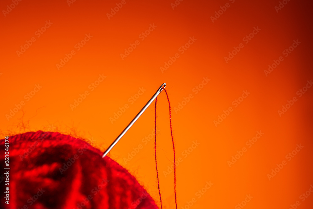 red skein of thread thrust needle on lush lava background. close up copy space red skein of thread thrust needle on lush lava background. close up copy space