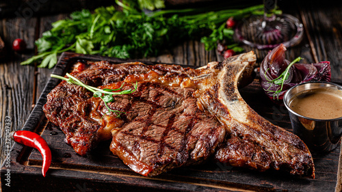 European cuisine in Ukrainian style. Large, juicy grilled T-Bone steak. Serving dishes in a restaurant on a wooden board with sauce. background image, copy space text photo