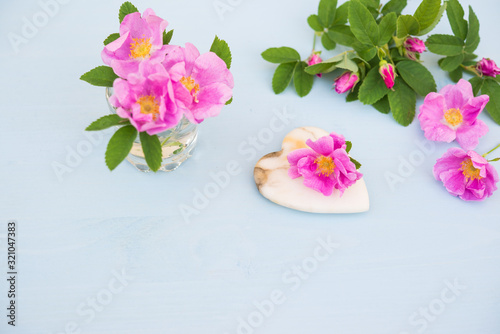 Rose. Pink flower with Heart of marble on an blue wooden table. Valentine background