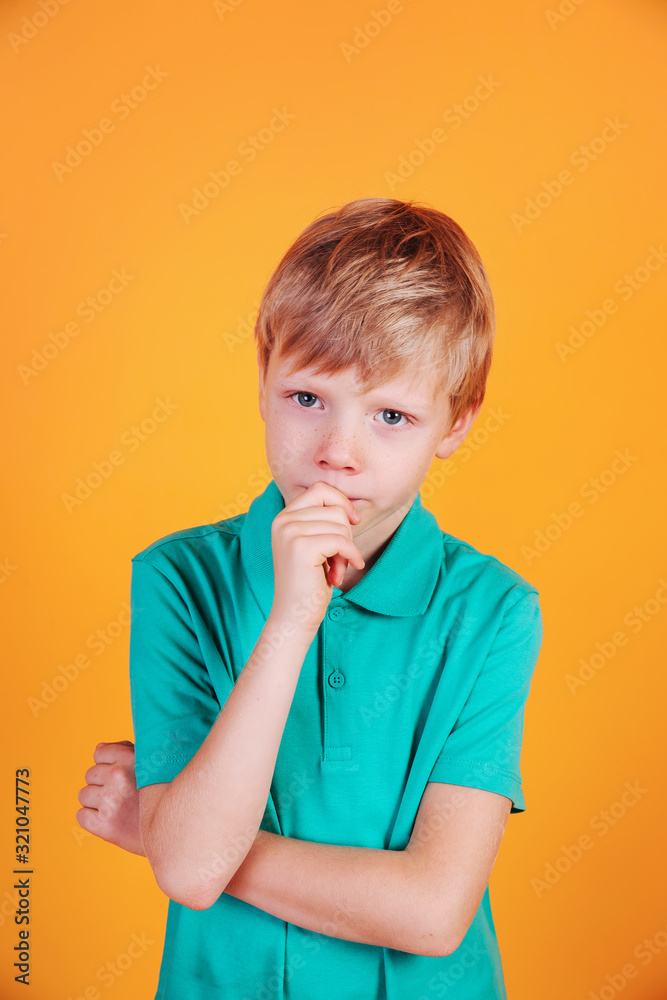 Thinking little boy child in turquoise t-shirt on yellow background. Thinking little boy child in turquoise t-shirt on yellow background.