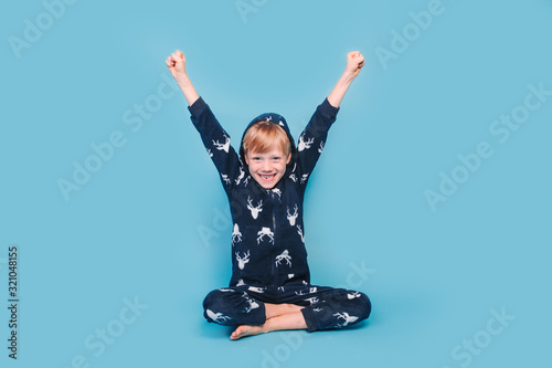 Happy little boy in warm pajamas waking up in the morning