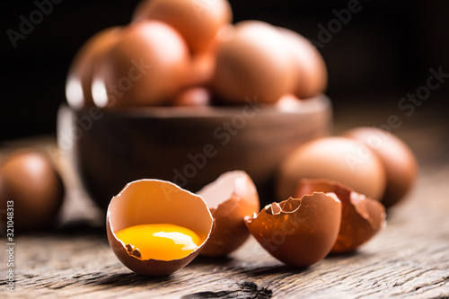 Broken chicken eggs with yolk on wooden table photo