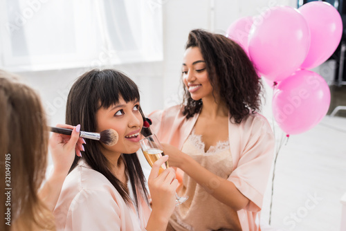 multiethnic girls making hair styling  makeup and drinking champagne on bachelorette party
