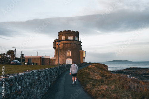 A Person Is Walking Past The Beach Tower In Portmarnock