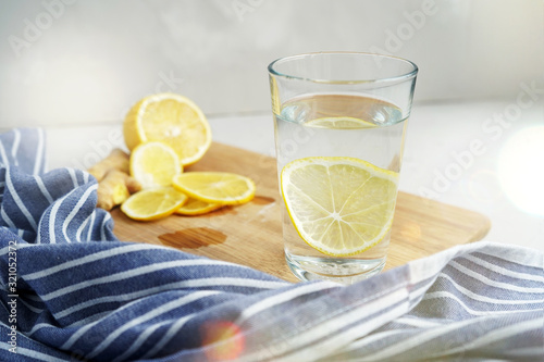 Refreshing drink with lemon on a gray background. Warm water with a slice of lemon next to a blue napkin