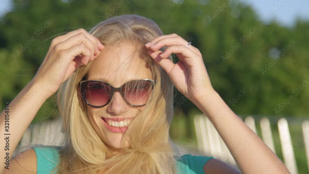SLOW MOTION, CLOSE UP, PORTRAIT, DOF: Young woman laughs while playing with her gorgeous long blonde hair. Playful Caucasian girl runs her hand through her hair while having fun in the idyllic park. SLOW MOTION, CLOSE UP, PORTRAIT, DOF: Young woman laughs while playing with her gorgeous long blonde hair. Playful Caucasian girl runs her hand through her hair while having fun in the idyllic park.