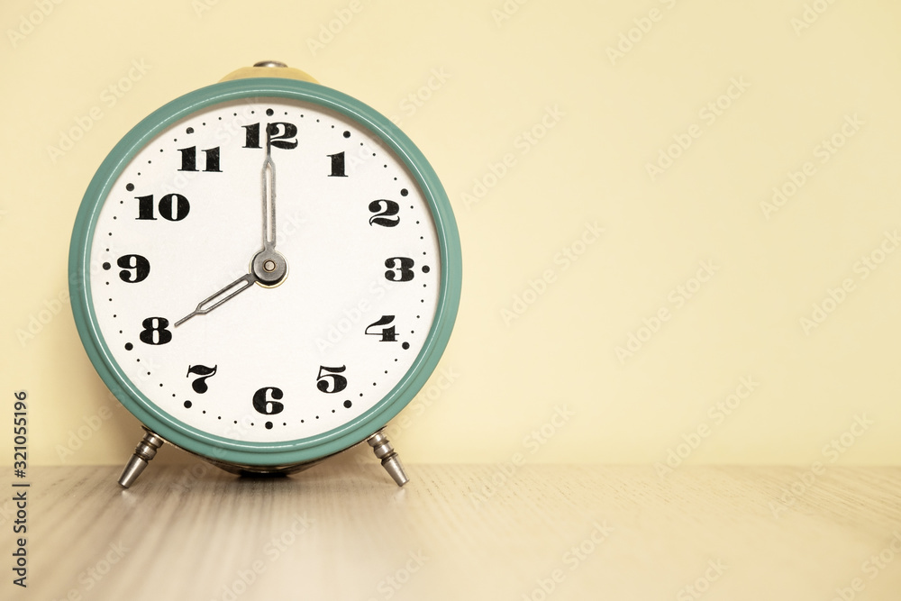 Fotka „Antique analog clock with hands set at 08:00. 20:00 The alarm clock  is on the table“ ze služby Stock | Adobe Stock