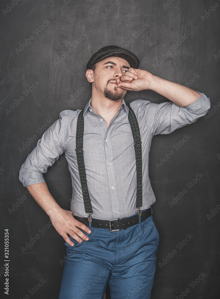 Handsome young man in retro style with cap on blackboard