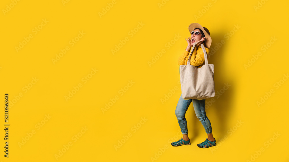 Portrait of an excited beautiful girl wearing dress and sunglasses holding shopping bags. Cheerful young woman with handbag on yellow background. Shopaholic shopping Fashion. Portrait of an excited beautiful girl wearing dress and sunglasses holding shopping bags. Cheerful young woman with handbag on yellow background. Shopaholic shopping Fashion.
