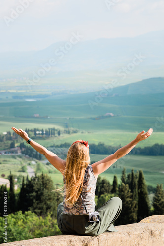 Young woman standing with her arms stretched enjoying the view of the Tuscany landscape
