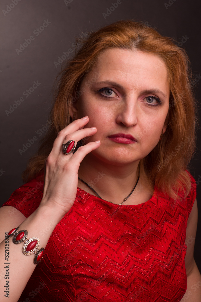 portrait of large blonde model in a red dress on a dark background in the Studio