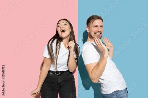 Crazy. Dancing, moving, having fun. Young and happy man and woman in casual clothes on pink, blue bicolored background. Concept of human emotions, facial expession, relations, ad. Beautiful couple.