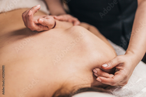 Chiropractor working on the shoulder joint of a patient - therapeutic massage