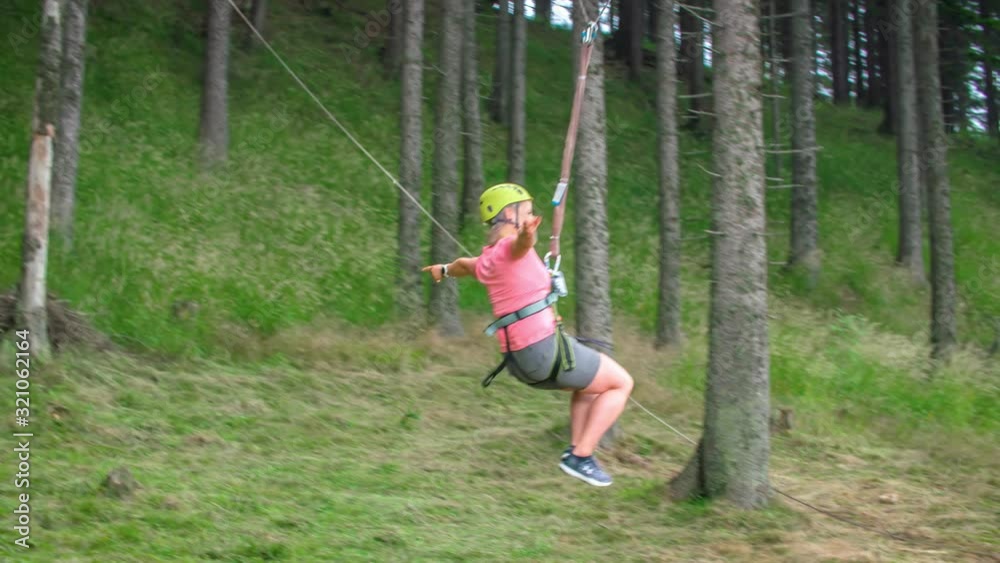 Adventurous young female feeling accomplished and happy by swinging freely on a big hanging swing between trees. Slow motion. Adventurous young female feeling accomplished and happy by swinging freely on a big hanging swing between trees. Slow motion.