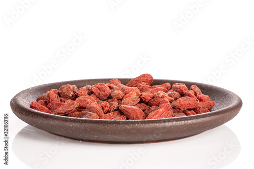 Lot of whole dried red goji with brown ceramic coaster isolated on white background