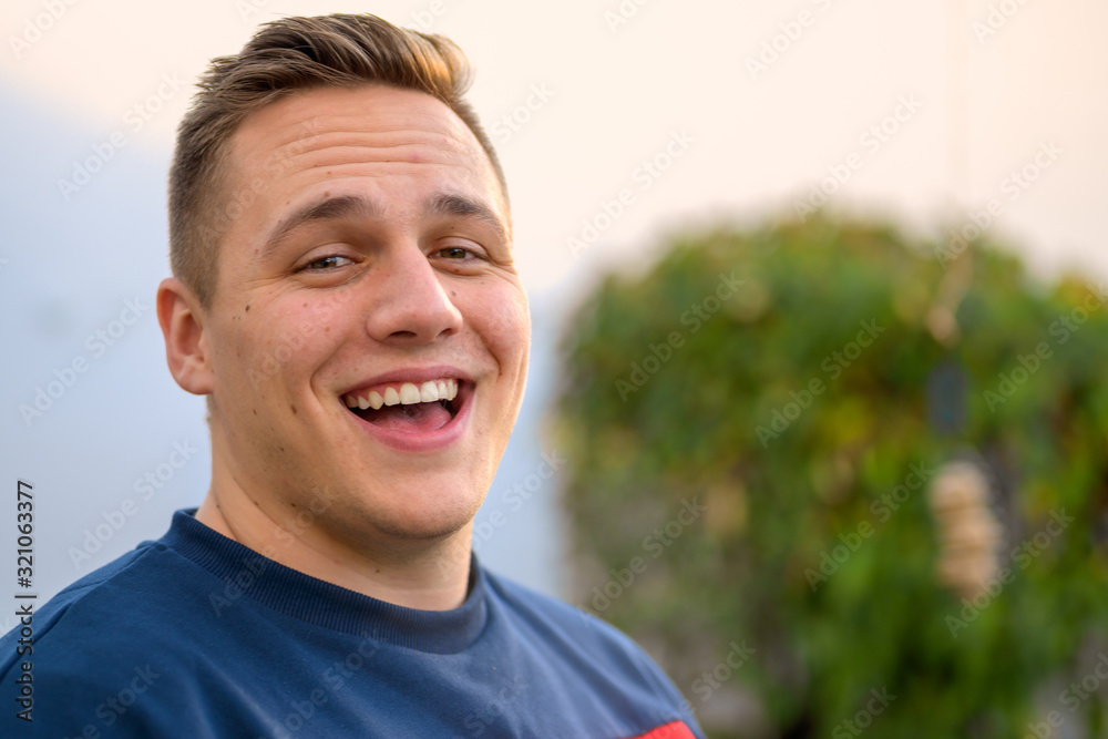 Jovial attractive young man laughing at the camera - obrazy, fototapety, plakaty 